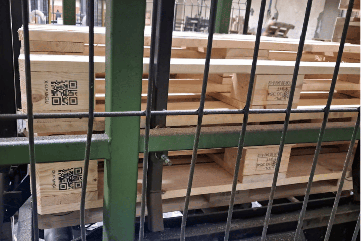 Przemysłowa drukarka do palet nanosi legalne oznakowanie IPPC na drewniane wsporniki w polskim zakładzie produkcyjnym.