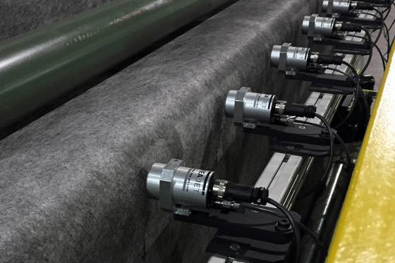 Wielogłowicowy system przemysłowy znakujący szeroką wstęgę włókniny na linii produkcyjnej.