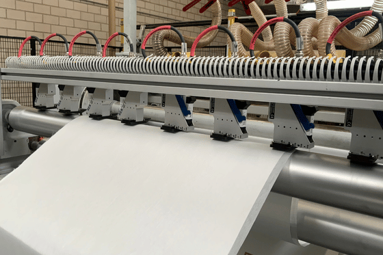 Głowica drukująca nanosząca datę produkcji na szarej włókninie technicznej.