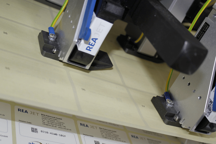 Jak dobrać technologię znakowania do rodzaju materiału Drukarka wysokiej rozdzielczości REA JET HR wykonująca precyzyjny nadruk na etykietach samoprzylepnych podczas procesu produkcyjnego.