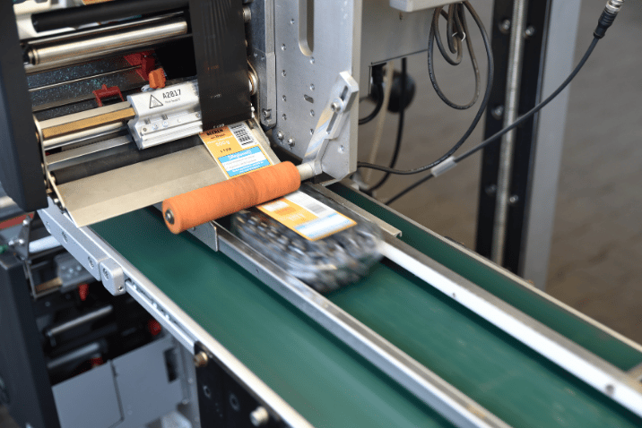 Przemysłowy system REA LABEL Print & Apply drukuje i nakłada etykiety z kodami oraz danymi identyfikacyjnymi na produkty poruszające się po linii produkcyjnej.