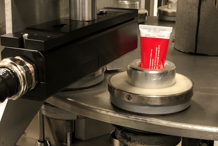 Nadruk daty i numeru partii na plastikowej tubie na przemysłowej linii produkcyjnej.