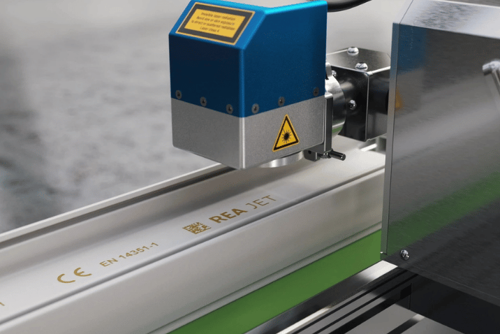 Laser REA JET wykonujący trwały kod 2D i oznaczenia techniczne na profilu przemysłowym.