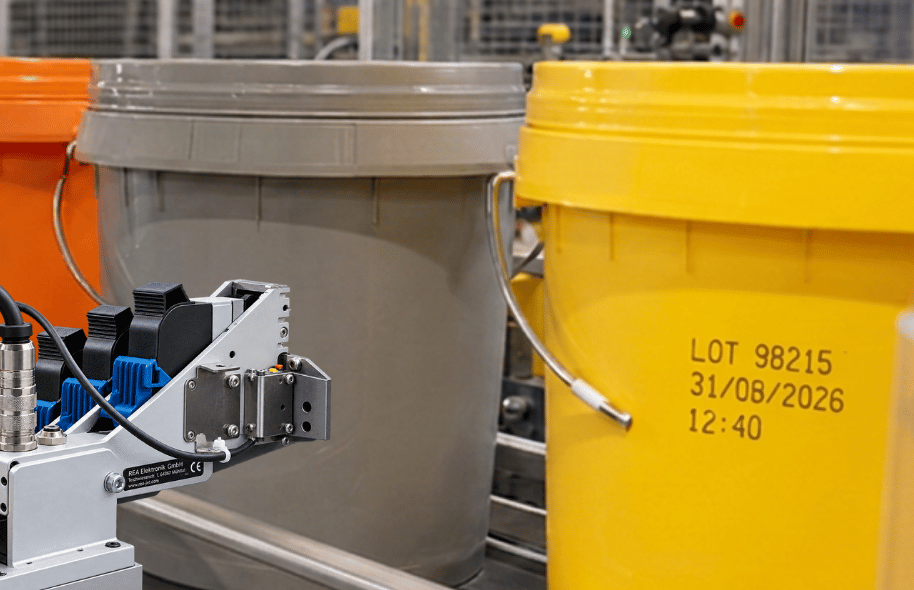Żółte plastikowe wiadro na linii produkcyjnej z nadrukowanym numerem LOT, datą i godziną