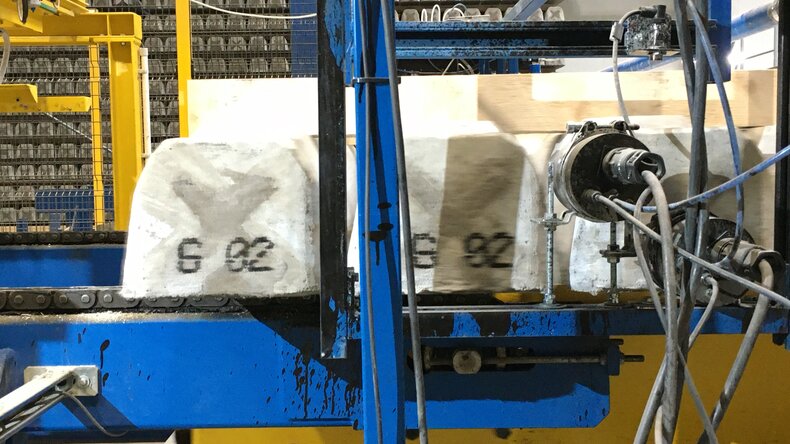 Elementy betonowe znakowane danymi produkcyjnymi podczas transportu przez linię przemysłową