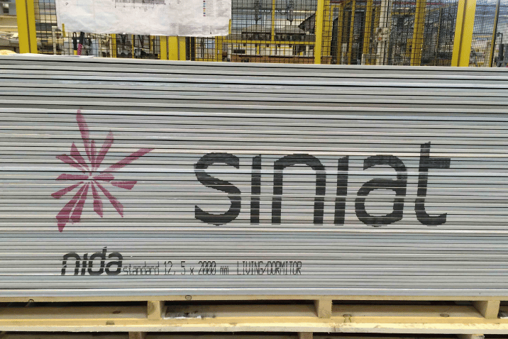 Duże logo producenta nadrukowane na stosie płyt gipsowo-kartonowych