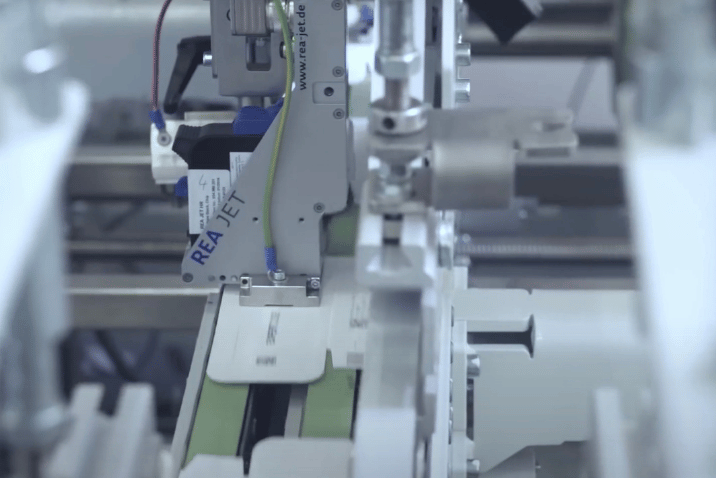 Aplikator etykiet REA zintegrowany z automatyczną maszyną produkcyjną