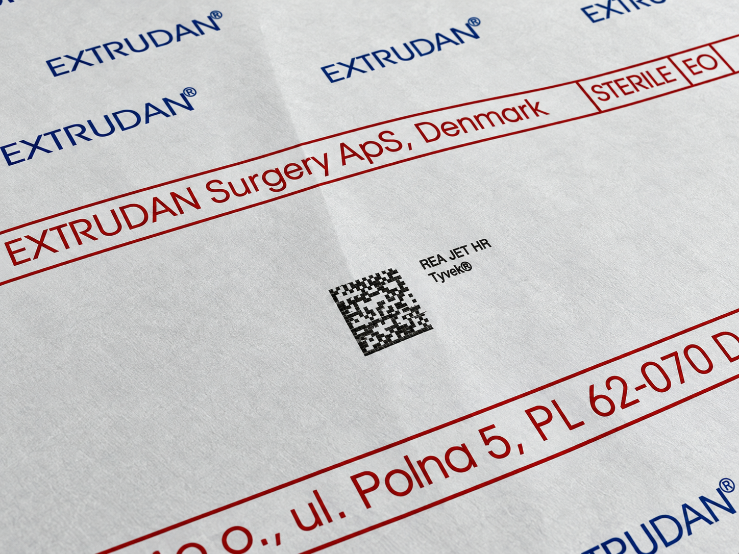 Zbliżenie na materiał Tyvek z kodem DataMatrix, nadrukiem REA JET HR oraz oznaczeniami EXTRUDAN i STERILE EO na opakowaniu medycznym.